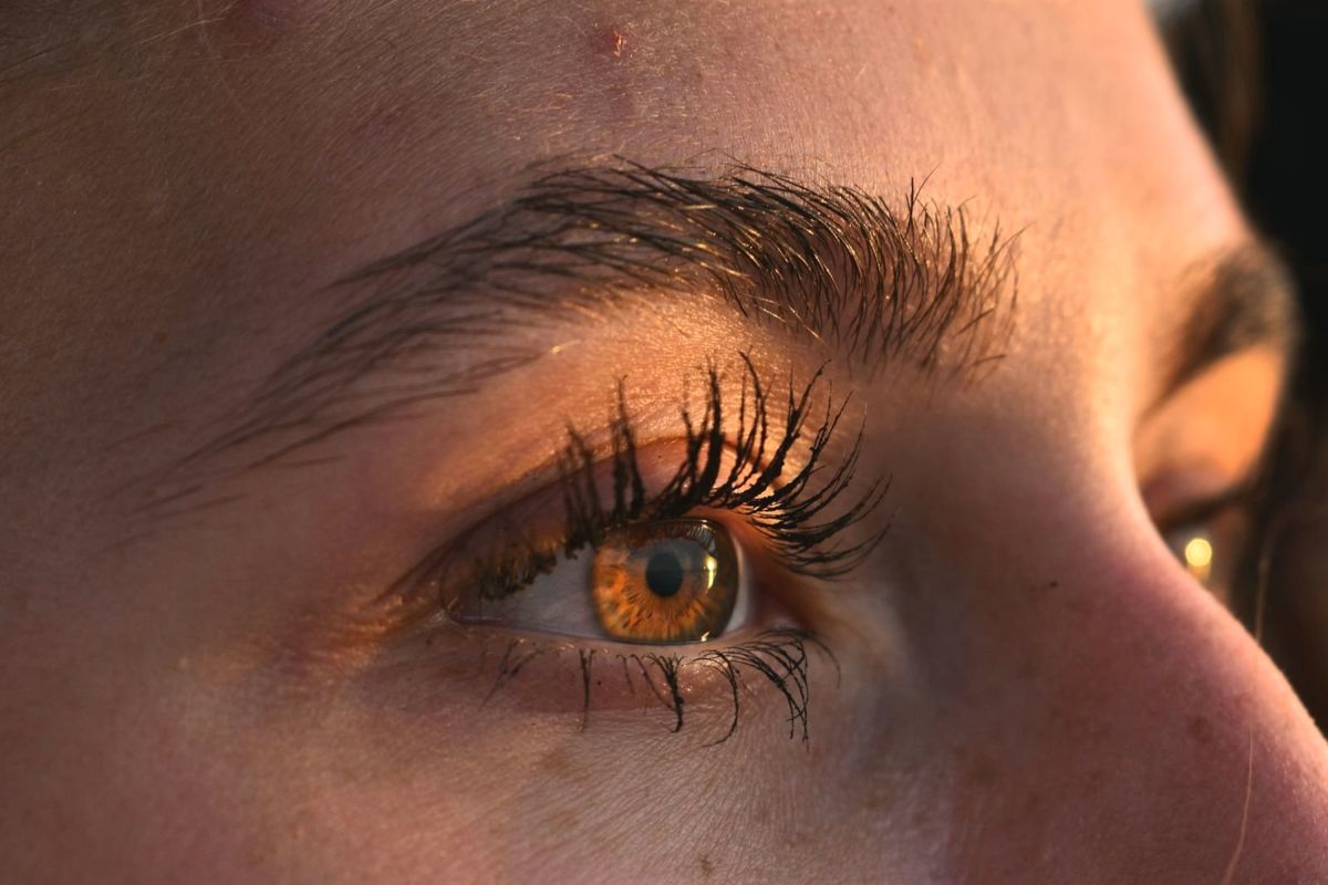 Symbolbild: Auge mit langen Wimpern in warmem Licht